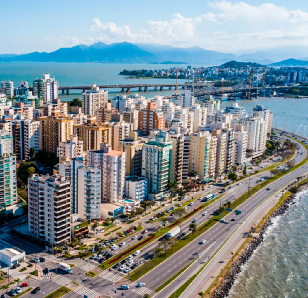 Aerial view of Belo Horizonte, Brazil, featuring modern buildings, busy streets, and a scenic shoreline with mountains in the background, showcasing the city's vibrant atmosphere.