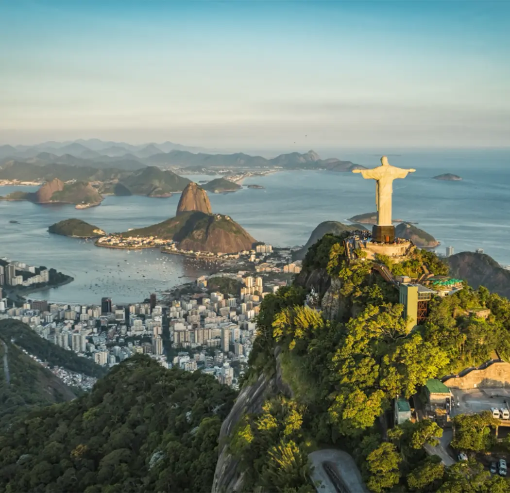 Aerial view of Christ the Redeemer statue atop Corcovado Mountain, overlooking the city of Rio de Janeiro and its coastline, showcasing the iconic landscape of Brazil.