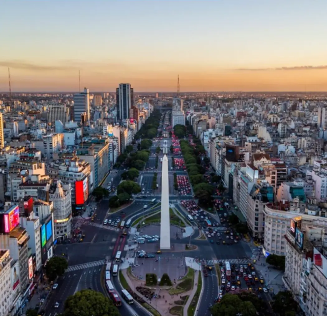 Aerial view of Buenos Aires, Argentina, showcasing the Obelisk in Avenida 9 de Julio, surrounded by bustling streets, green trees, and a vibrant city skyline.