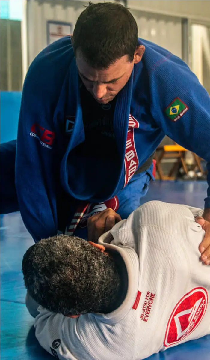 Two practitioners training in Jiu-Jitsu at a top BJJ camp in South America, wearing blue and white gis during a technique session.