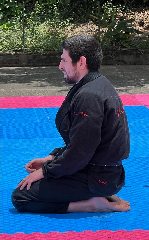 Alex Ecklin seated on the mats, deeply focused during a Brazilian Jiu-Jitsu training session at BJJ Camp.