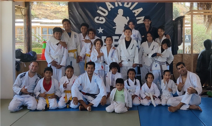 A group of Brazilian Jiu-Jitsu students and instructors posing together after a training session while traveling.