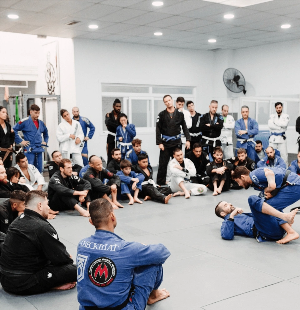 A Brazilian Jiu-Jitsu class with students and instructors training and learning techniques while traveling.