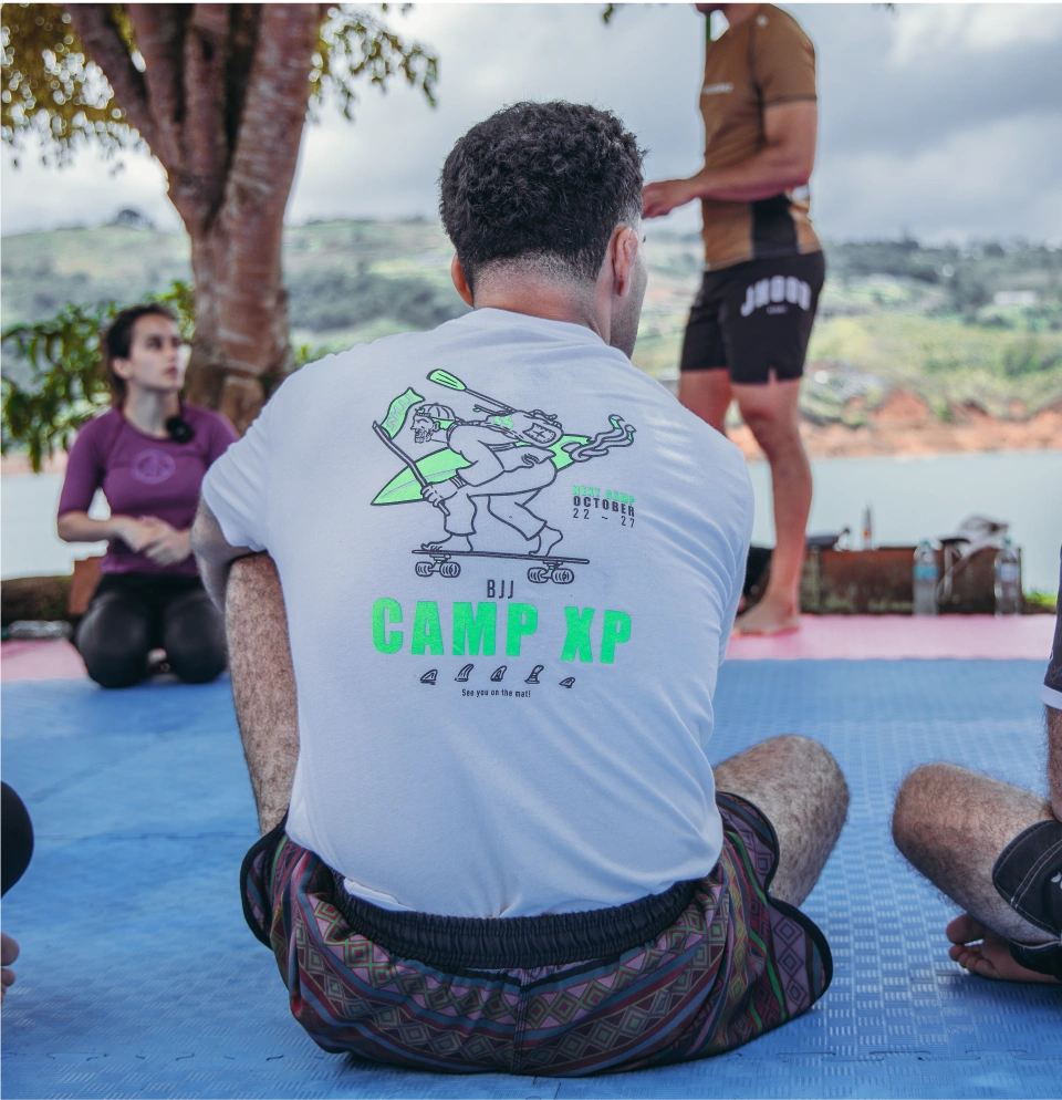 A group of people training BJJ outdoors near a scenic lake, blending BJJ training while traveling with nature.