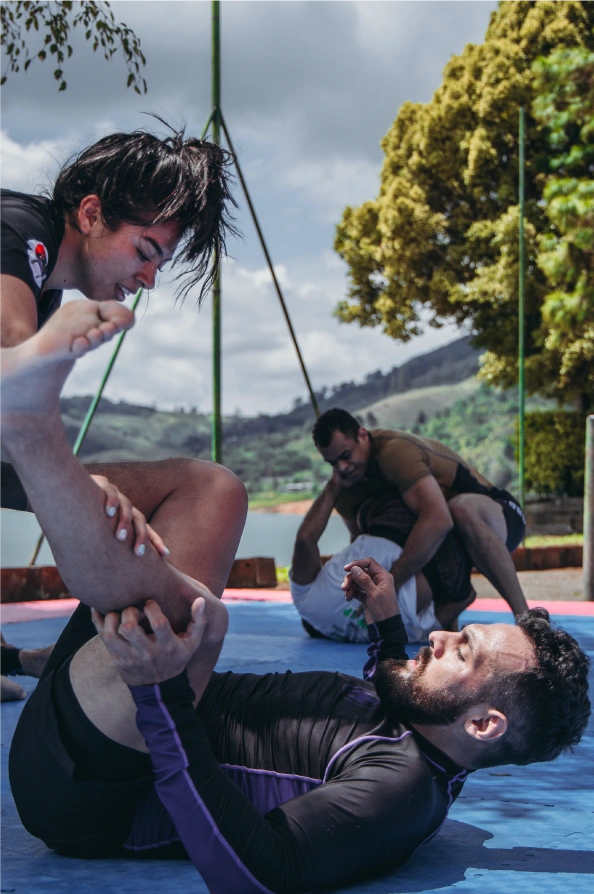 Leonidas Benjumea in a white gi, engaging with young Jiu-Jitsu students during a training session in Colombia.