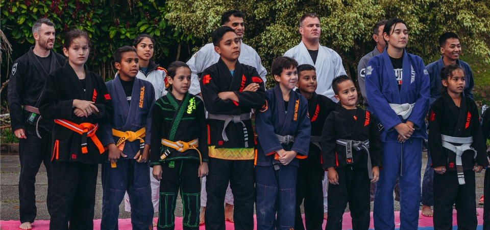 A group of young Colombian Jiu-Jitsu practitioners posing with world champions at BJJ Camp XP, showcasing empowerment and community.