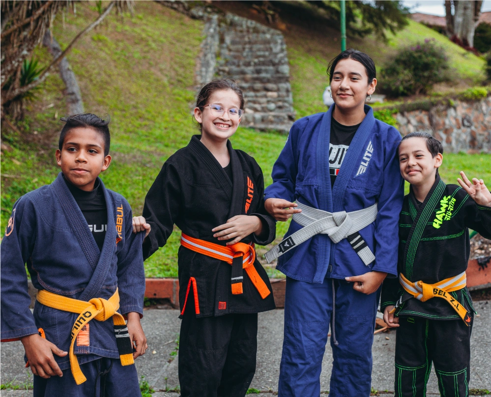 Four young Colombian Jiu-Jitsu students in gis, smiling and posing after a training session with world champions.