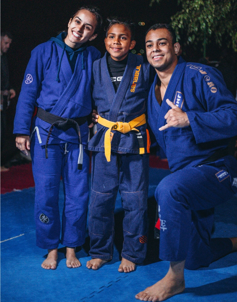 A young Colombian Jiu-Jitsu student proudly posing with two world champions during a transformative training session at BJJ Camp XP.