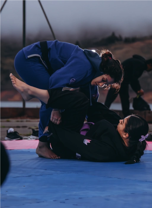 BJJ Camp participants training on mats outdoors near a lake, practicing Jiu-Jitsu techniques under the sun.