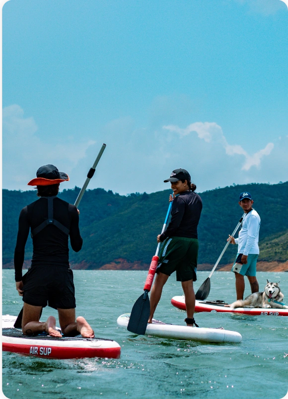 BJJ Camp Pricing.Adventure Beyond the Mats BJJ Camp pricing activity showing campers paddleboarding with a dog on a scenic lake.