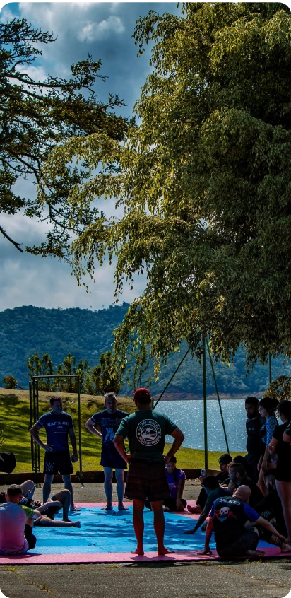 Transparent BJJ Camp Pricing.All-Inclusive Adventure BJJ Camp pricing includes lakeside training sessions with a coach addressing campers under the trees.