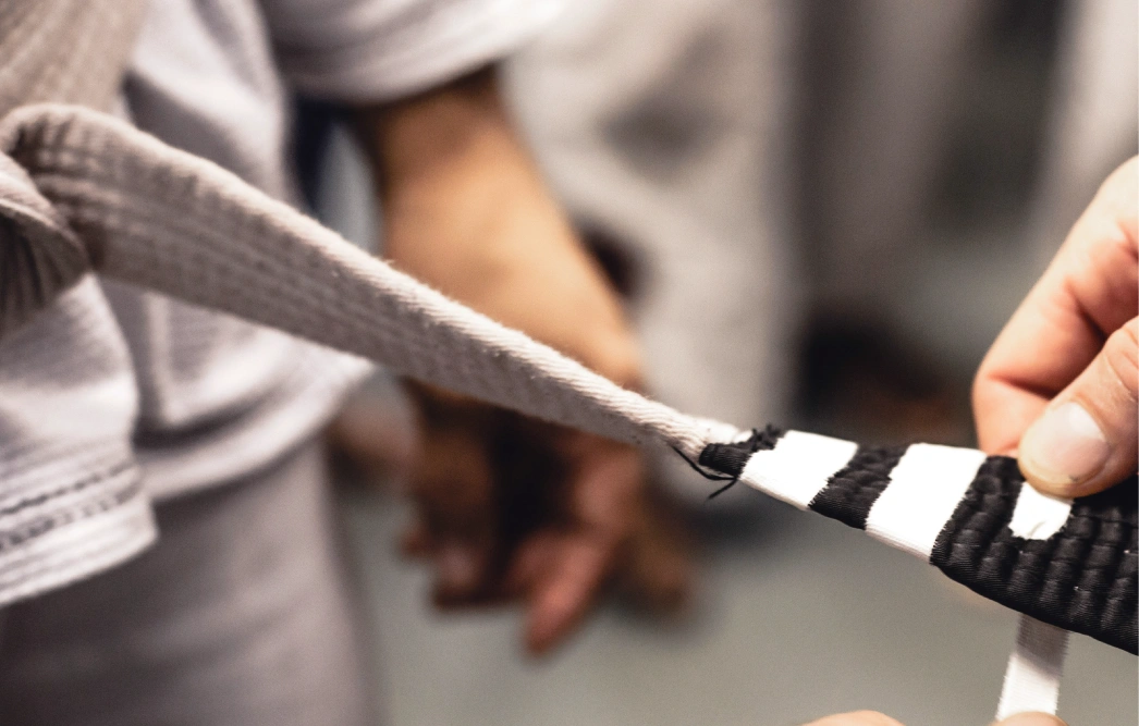Close-up of Brazilian Jiu Jitsu black belt being tied, representing training at a Brazilian Jiu Jitsu Camp in Peru.